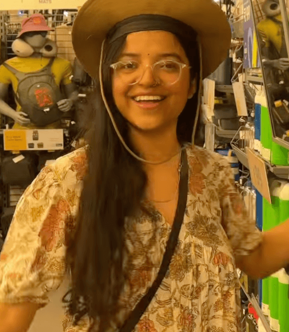 Shivangi at Decathlon grinning in a wide-brim tan sun hat and floral blouse